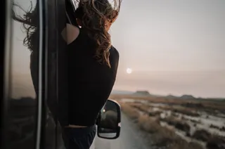 Girl with aching hair bends from camper windows