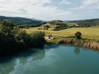 A reception from a lake and a camperBoys camper next to the air. A woman seems to be sitting in the open camper.