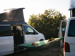 Campsite: One man is situated in a green hammock stretched between two campers.