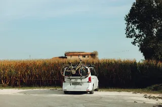 Camper with bicycles in front of a corn field in Italy: If the water tank in the camper is clean, the trip can go!